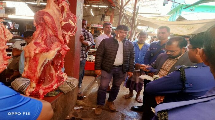 কাপ্তাই নতুনবাজারে ভোক্তা-অধিকার সংরক্ষণ অধিদপ্তরের সহকারী পরিচালক রানা দেবনাথ একটি মাংসের দোকানে মূল্য তালিকা যাচাই করছেন এবং পুলিশ সদস্যরা পাশে দাঁড়িয়ে আছেন।