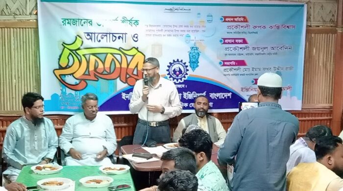 Engineers and guests gathered at a dining table for an Iftar mahfil organized by IDEB in Kaptai, with a banner in the background.